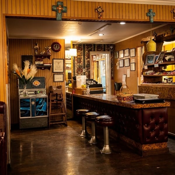 Cozy restaurant interior with wood paneling, a bar with stools, and framed artwork.