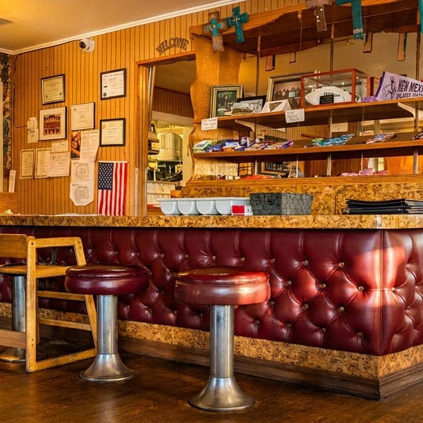 Interior view of a diner with a red tufted counter, bar stools, and wood paneling.
