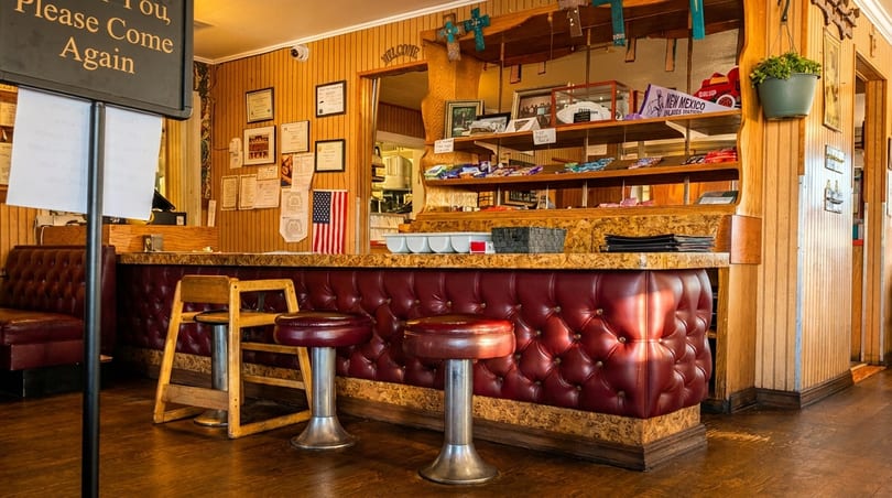 Interior view of a diner with a red tufted counter, bar stools, and wood paneling.